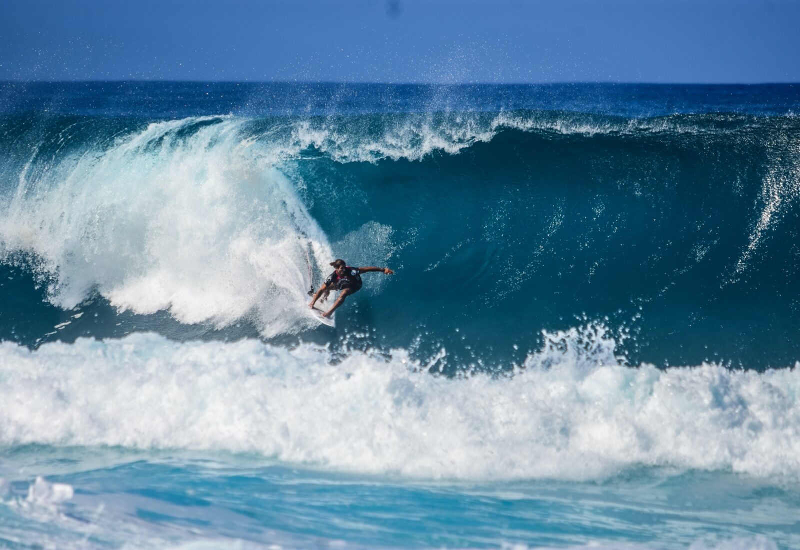 Surfer riding a massive blue wave