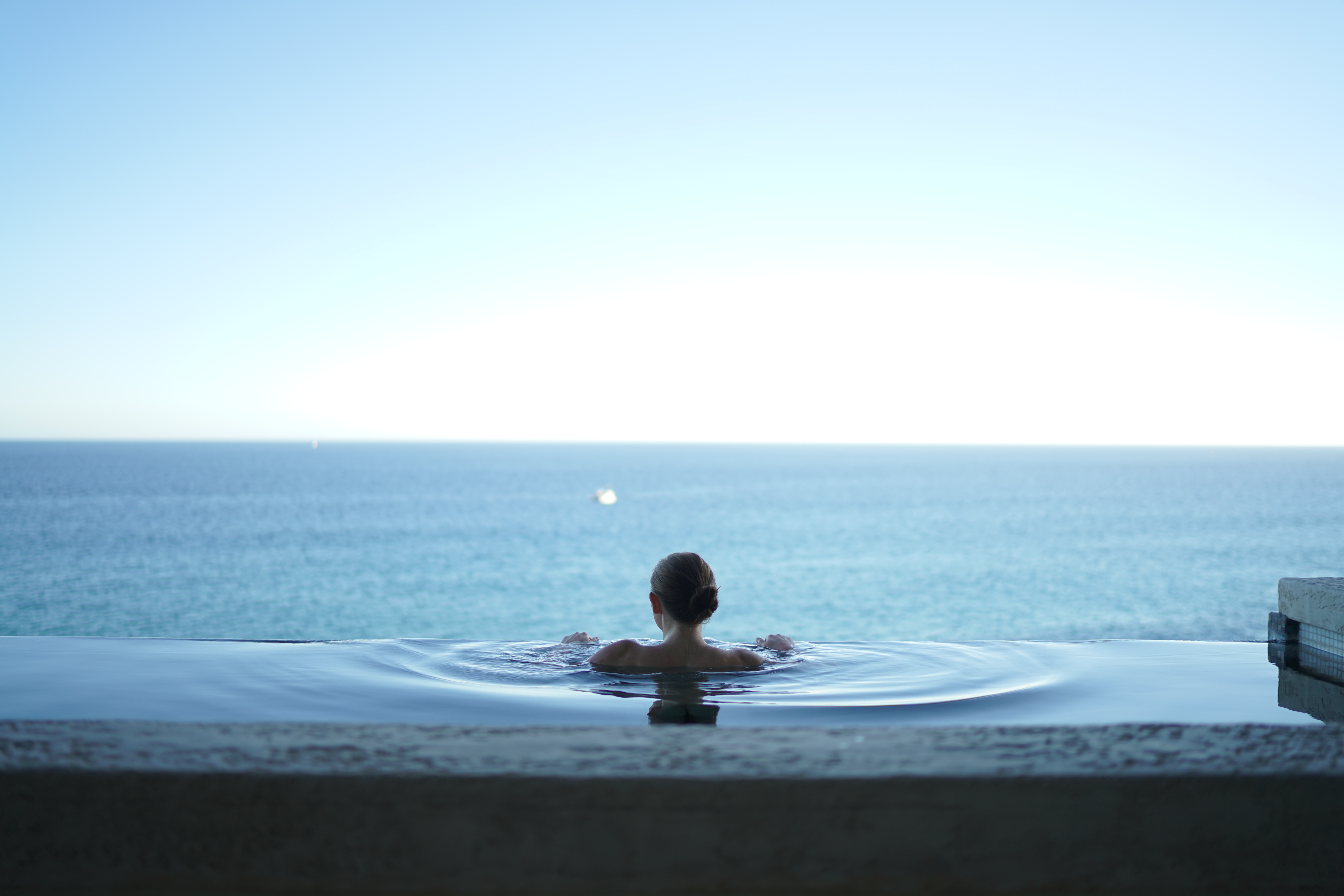 A lady immersed in an infinity pool, an infinite expanse of water.