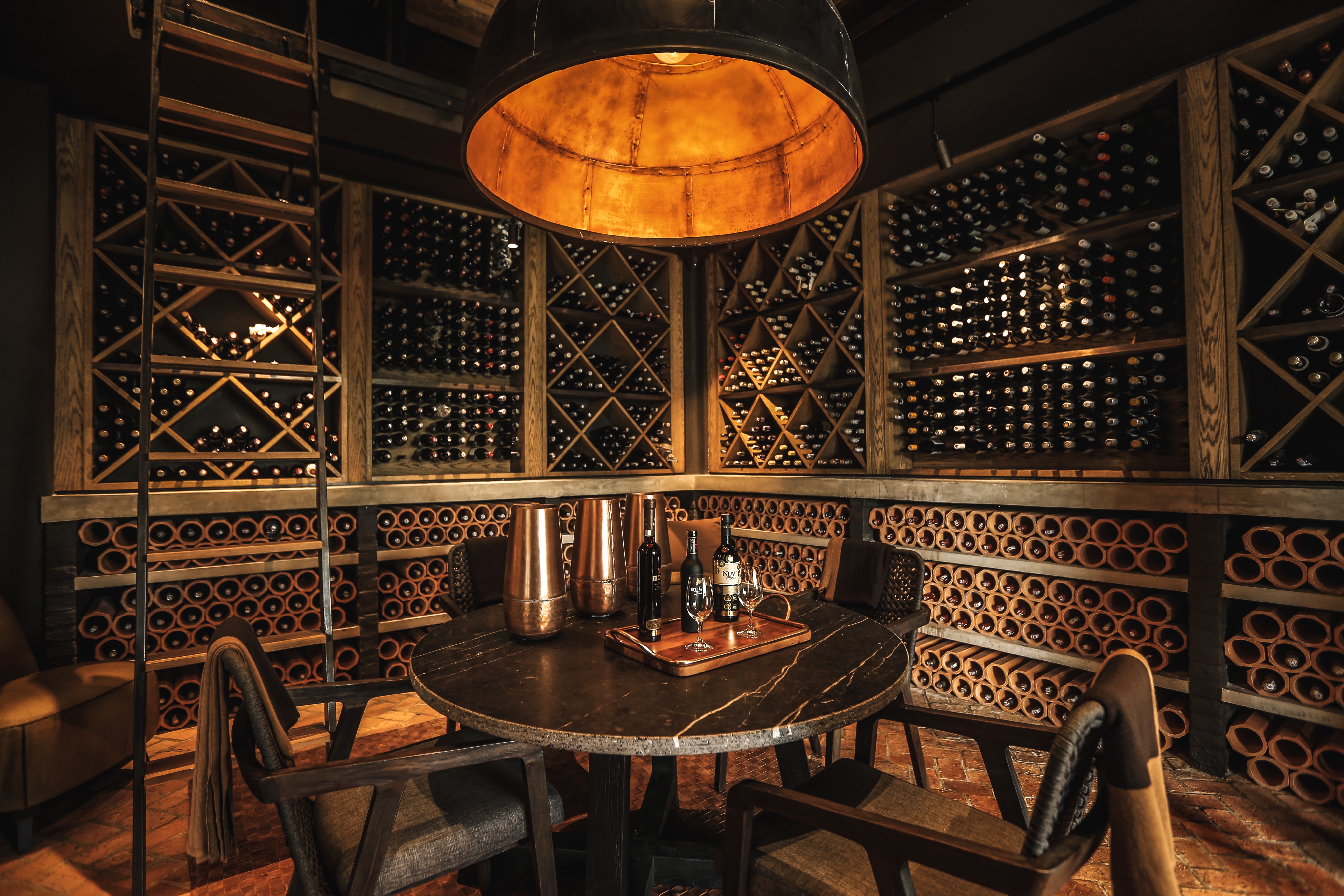 A wine cellar furnished with a sturdy table made of rich brown wood, accompanied by a set of chairs