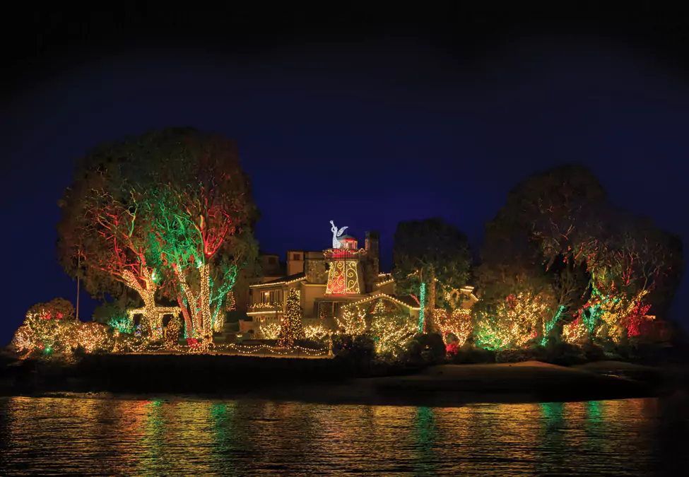 Large Newport Beach Home Viewed from the Water with Christmas Lights in White, Red, and Greens, with large Angel Light Sculpture Blowing in Trumpet