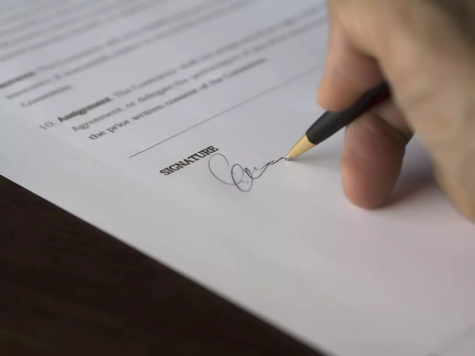 Hand signing a signature on a contract in pen ink.
