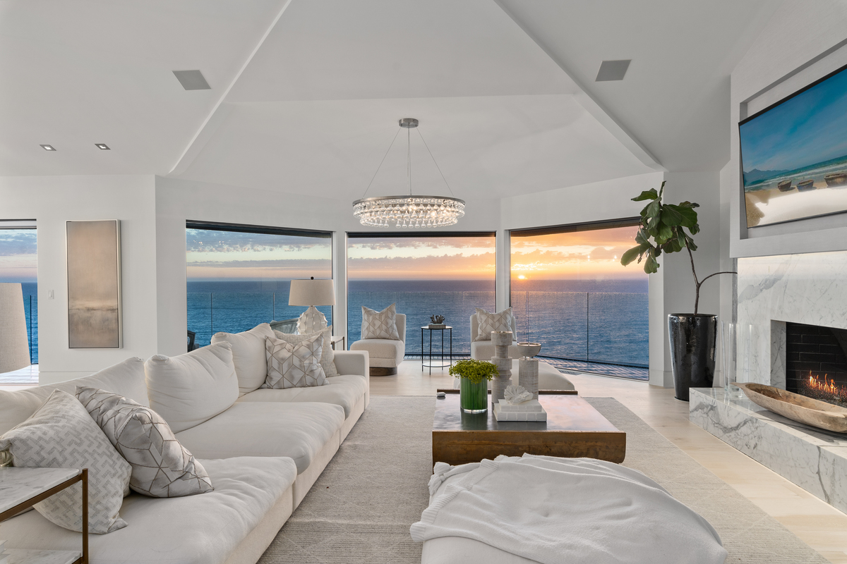 Luxury home interior with fireplace overlooking the Pacific Ocean at sunset