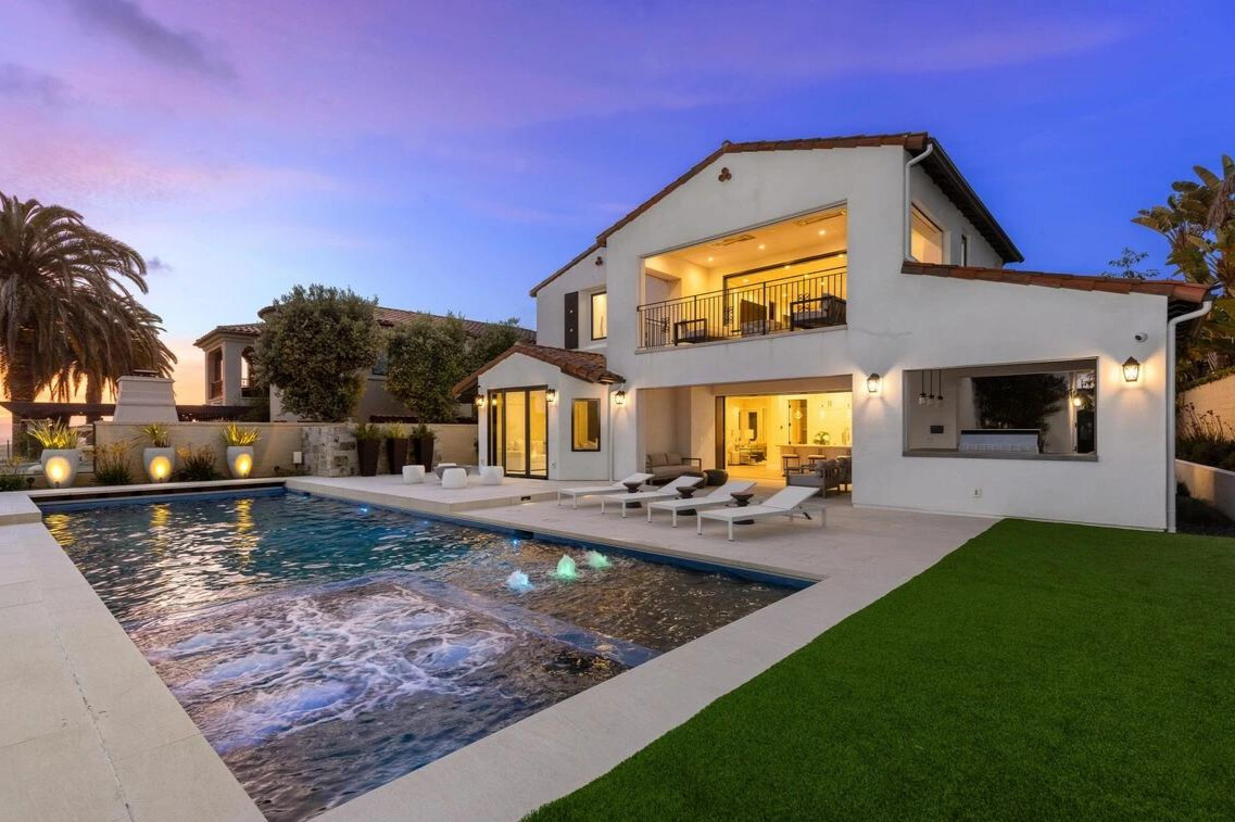 Luxurious OC home with backyard pool at sunset.