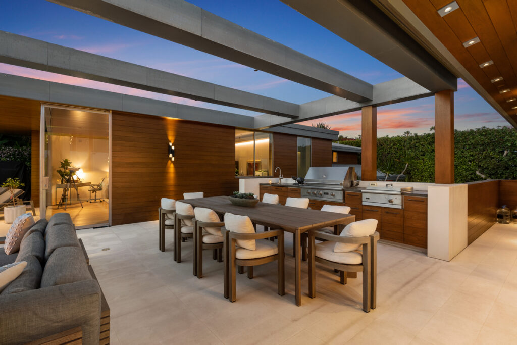 Elegant outdoor luxury living area with built-in BBQ/kitchen, dining space, and lounge in Coastal Orange County, embodying the lavish lifestyle of Newport Beach, Laguna Beach, and Corona del Mar's prime real estate.