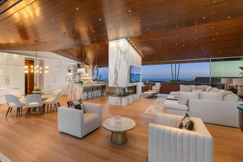 Luxury open-concept living room featuring a floor-to-ceiling fireplace and expansive ocean views, showcasing high-end real estate in Coastal Orange County's Newport Beach, Laguna Beach, and Corona del Mar.