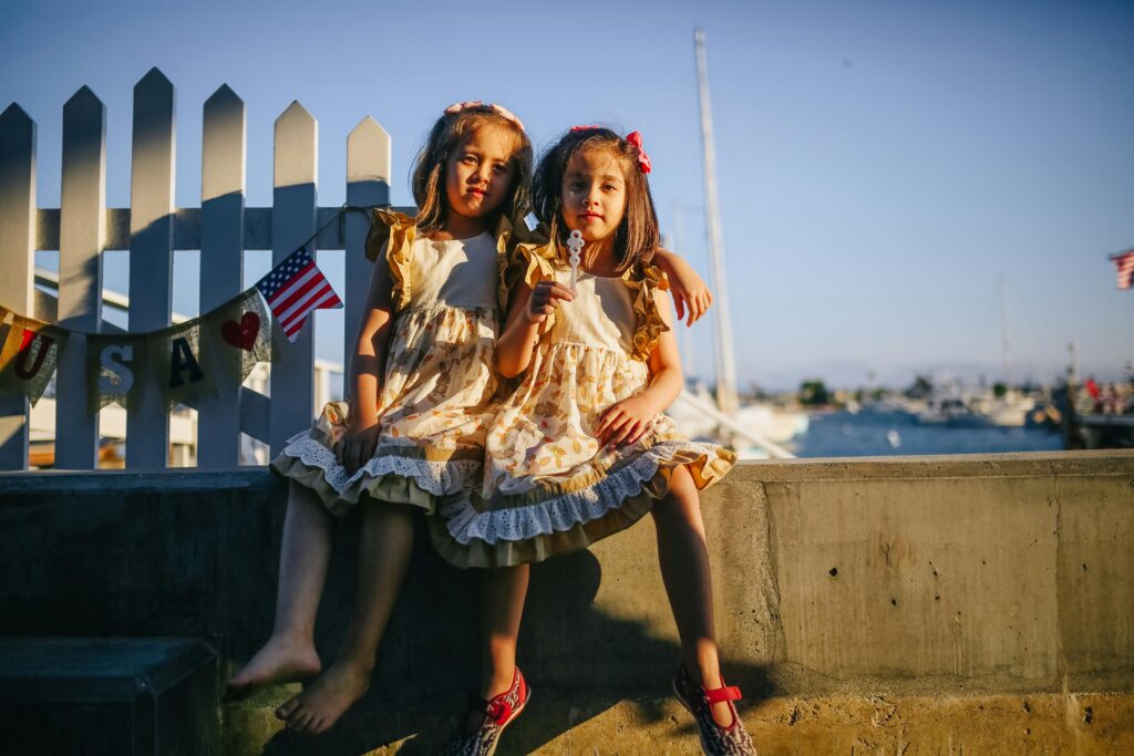 Two young girls sitting by the ocean in Newport Beach, California