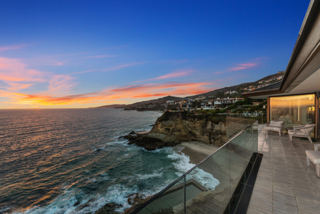 Stunning photo capturing the crashing waves and colorful sunset view from the patio of 32 N La Senda, a multi-million dollar luxury home for sale in Newport Beach listed by top Orange County luxury real estate agents, the Stavros Group.