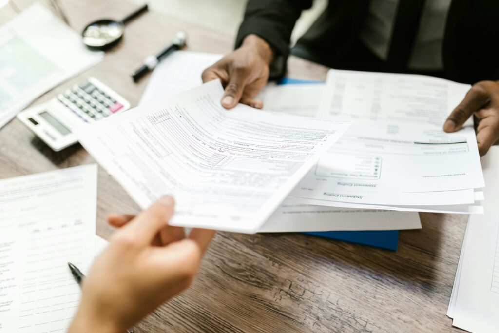 People passing papers across a desk, representing a home insurance policy transaction