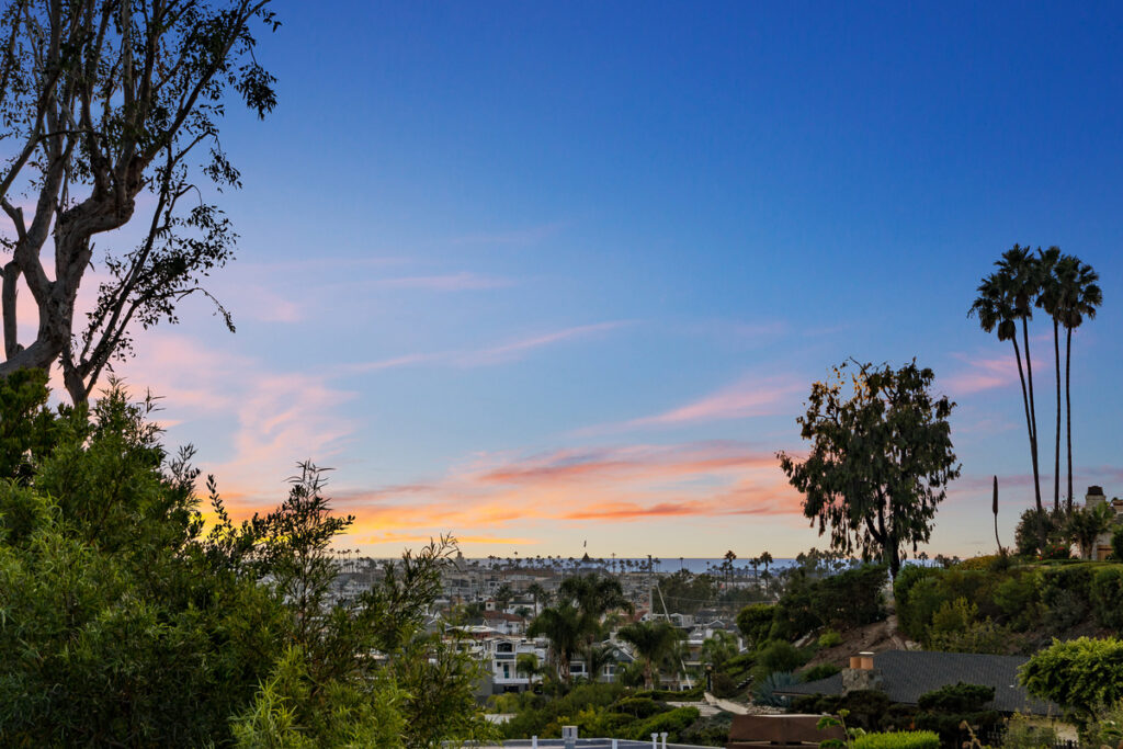 Backyard of a luxury home in Corona del Mar with breathtaking sunset colors and panoramic ocean views, perfectly capturing the appeal of Orange County coastal living.