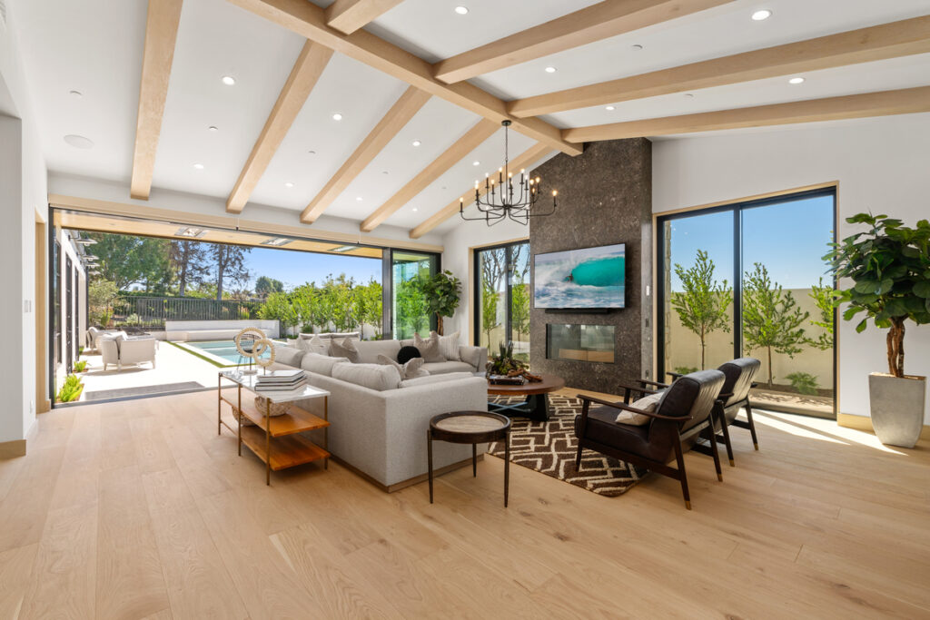 Open-concept great room in a Corona del Mar luxury property, featuring cathedral ceilings, expansive sliding glass doors for seamless indoor-outdoor living, and elegant staging by the Stavros Group.