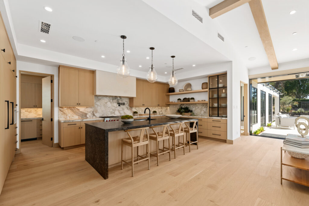 Modern kitchen in a Corona del Mar luxury home, featuring island bar seating, high-end appliances, and professional staging to showcase its entertaining potential, listed by the Stavros Group.