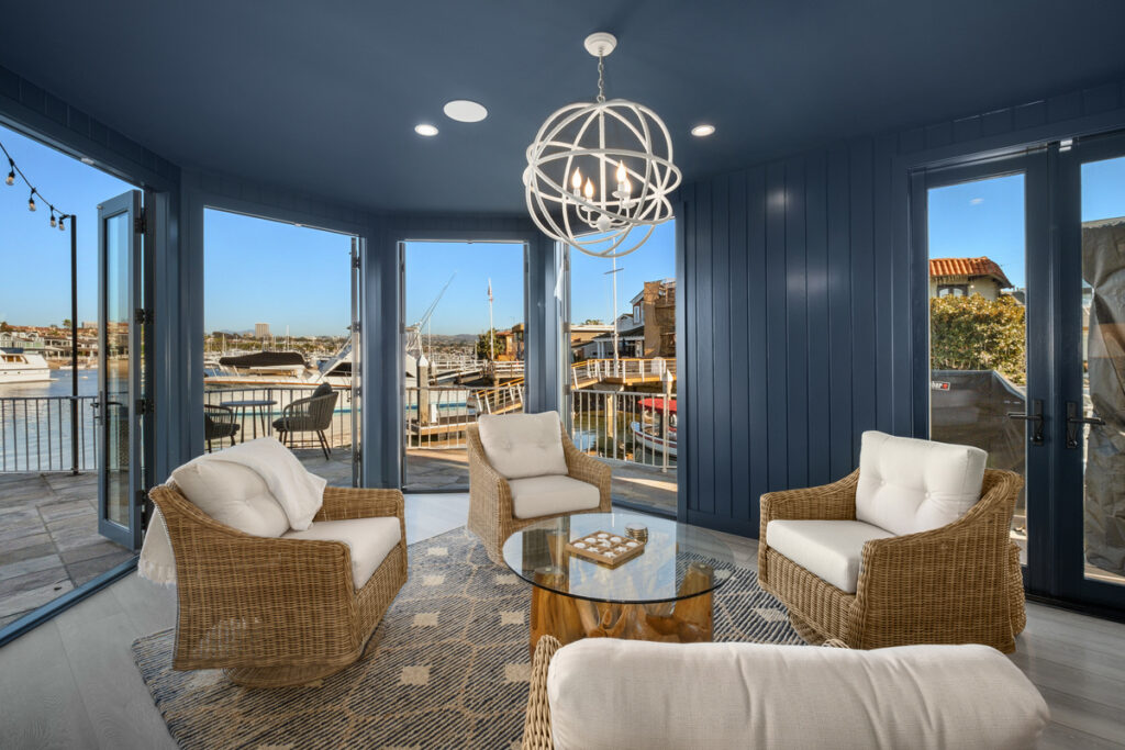 Chic sitting room with dark colorful paint and chairs looking out bay windows to the water in Newport Beach luxury home