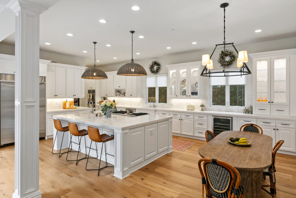 Kitchen and eat-in dining area with white cabinets and countertops in sell home Newport Beach luxury realtors