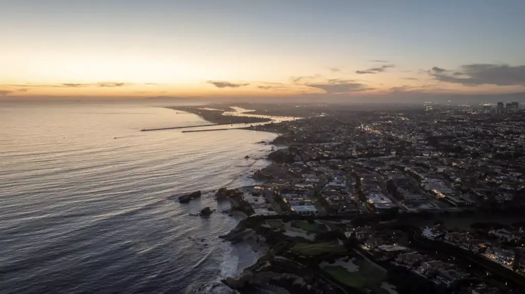 Aerial view of Orange County luxury properties and the coastline with Pacific Ocean at sunset.