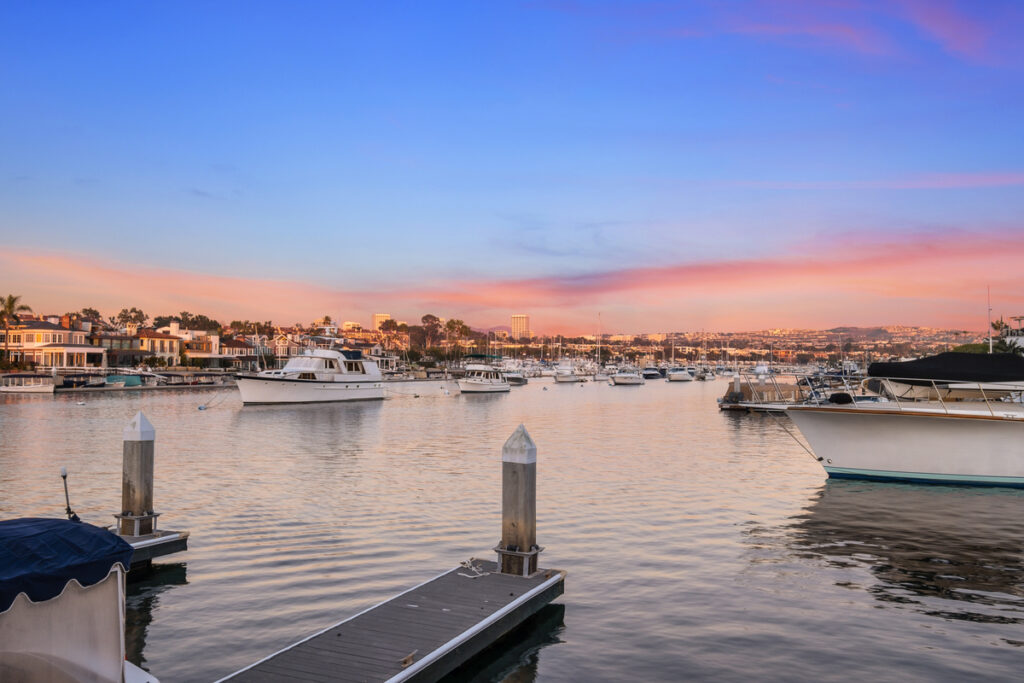 Boats and sunset colors on the water in Newport Beach real estate homes for sale for buyers and top local Realtor real estate agents