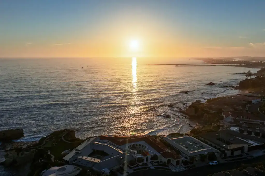 Drone image of Corona del Mar luxury homes at sunset with the ocean beyond