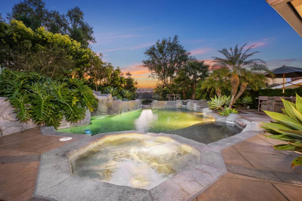 Pool and spa shrouded in mature landscaping with outdoor living area sold by top OC luxury realtors the Stavros Group