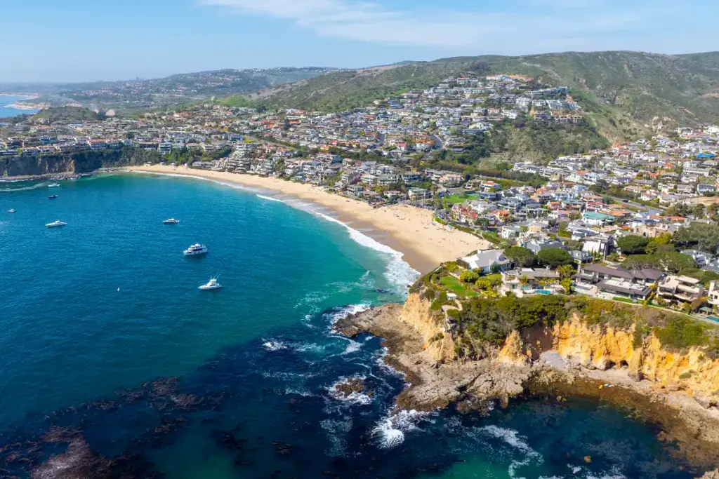 Aerial view of the Laguna Beach coastline, ocean and beaches, with luxury real estate lining the coast for home sellers and buyers in Orange County