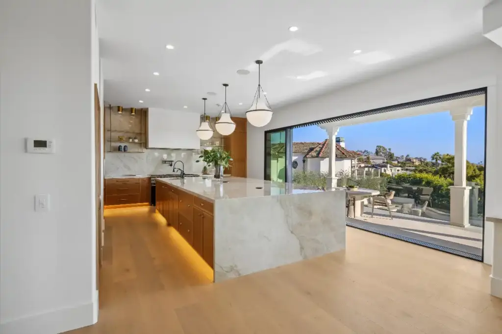 Kitchen island and bifold doors to outdoor patio in luxury real estate listing that is prepared and staged for the best sale price by top Newport Beach Realtors