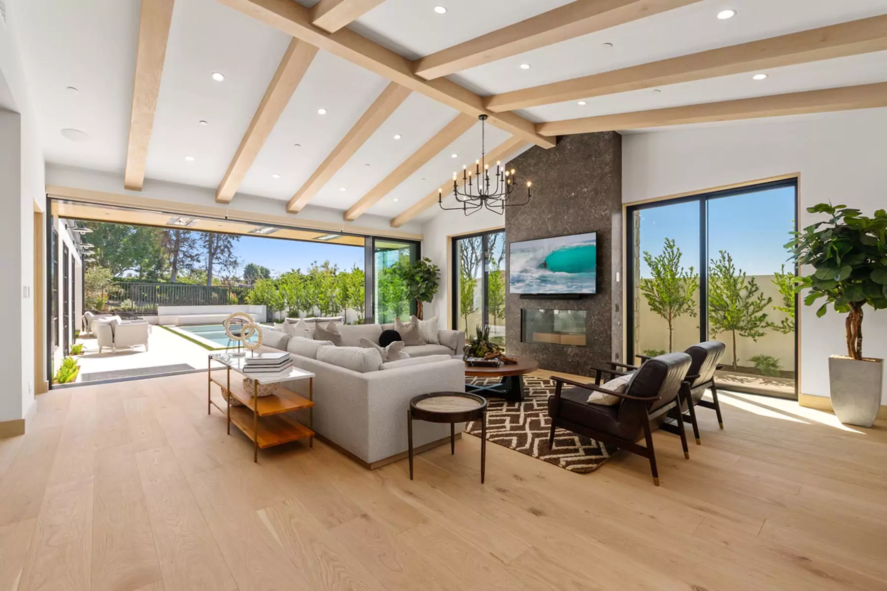 Interior living room with vaulted ceiling and outdoor pool, at a home sold by the best luxury listing agent in Orange County