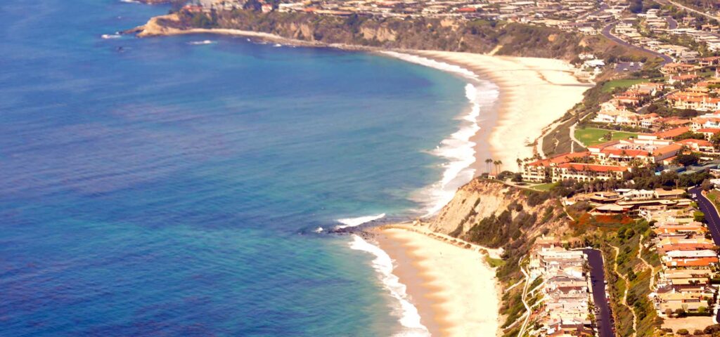 Aerial view of the beach and bluffs where homes for sale in Monarch Bay, Dana Point are listed by the best local luxury realtors agents at The Stavros Group